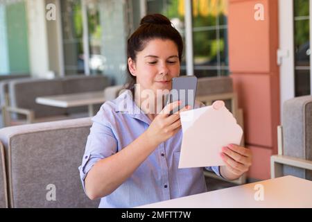 Nahaufnahmen von fröhlicher Frau, Fotografie von Gutschein-Geschenk. Stockfoto