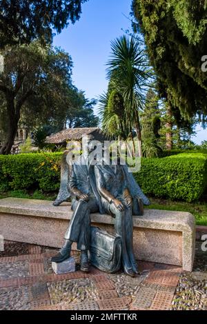 Messingstatue von zwei Personen, die auf einer Bank im Parco Florence Trevelyan sitzen, eine der wichtigsten Sehenswürdigkeiten des Touristenziels Taormina. Stockfoto