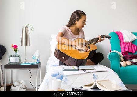 Ein Teenager spielt Gitarre in ihrem Schlafzimmer. Stockfoto