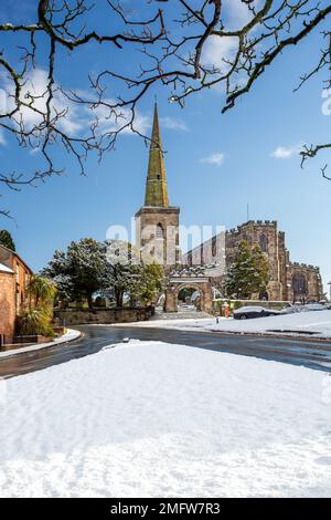 St. Mary's Church in Astbury in der Nähe von Congleton Cheshire England mit den Hütten auf dem schneebedeckten Dorfgrün im Winter Stockfoto