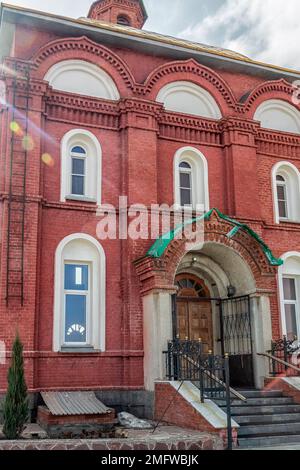 Teil der Mauer mit Fenstern und Eingang zur Kirche der Fürsprache der Heiligen Theotokos. Foto aufgenommen in Kopeysk, Chelyabinsk regio Stockfoto