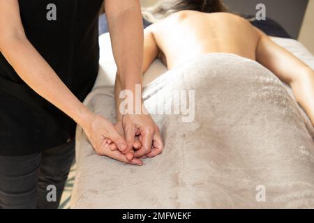 Massagetherapeutin, die weibliche Ol-Massagen des Handdrucks im Spa-Salon durch eine professionelle Masseurin durchführt Stockfoto