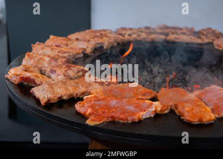 Prozess des Kochens von Fleischsteaks auf rundem Brazier - Nahaufnahme Stockfoto