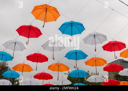 Bunte Regenschirme hängen beim Outdoor-Festival am bewölkten Himmel Stockfoto