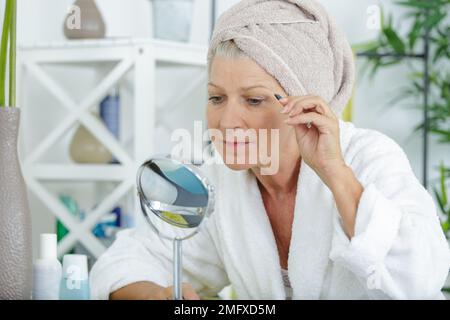 Seniorin, die Augenbrauen korrigiert Stockfoto