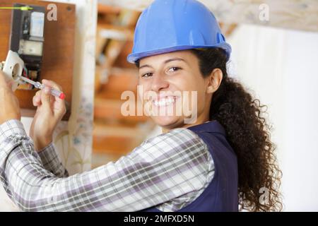 glücklich weibliche Builder mit Schraubendreher fixieren Steckdose im Haus Stockfoto