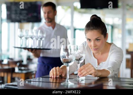 Frau, die Gläser im Restaurant putzt Stockfoto