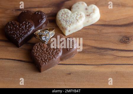 Herzförmiger Ring mit Schokolade auf einer Holzschachtel Stockfoto