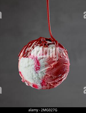 Vanille- und Erdbeereis mit Schokoladensoße auf grauem Hintergrund Stockfoto