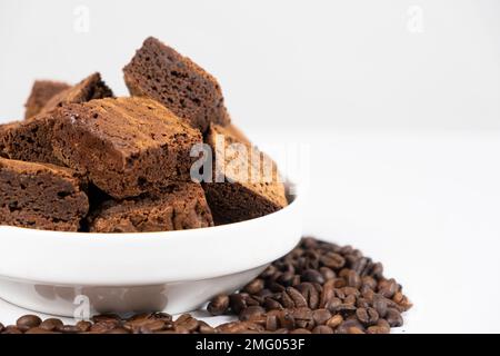 Schokoladenkuchen in Quadrate auf weißem Teller, Brownie und Kaffeebohnen, Kopierbereich für Text Stockfoto