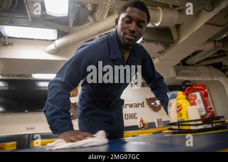 220820-N-FD648-1018 ATLANTISCHER OZEAN (20. August 2022) Feuerwehrmann Seaman Dillan Potts, der dem Arleigh-Burke-Klasse-Raketenzerstörer USS Farragut (DDG 99) zugeteilt wurde, wischt Tische auf dem Schiffsdeck ab, 20. August 2022. Farragut ist Teil der George H.W. Bush Carrier Strike Group, einem integrierten Kampfwaffensystem, das überlegene Kampffähigkeiten bietet, um Amerikas Gegner abzuschrecken und gegebenenfalls zu besiegen, um die nationale Sicherheit zu unterstützen. CSG-10,DDG99,DEPLOYMENT,Farragut,GHWBCSG,US Navy, Stockfoto
