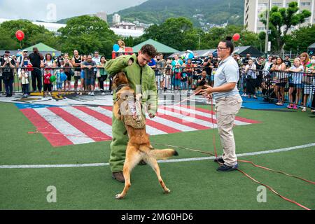 Master-at-Arms-1.-Klasse Torye Cugal führt mit ihrem Hund Frank C123 und Master-at-Arms-3.-Klasse Christian Moore bei der National Night Out 2022-Veranstaltung im Commander, Fleet Activities Sasebo Nimitz Park am 22. August 2022 eine Demonstration durch. National Night Out ist eine jährliche Veranstaltung, die Partnerschaften zwischen Polizei und Gemeinwesen und Nachbarschaftskameradschaft fördert und in Tausenden von Gemeinden aus allen fünfzig Bundesstaaten, US-Territorien und Militärstützpunkten weltweit stattfindet. Stockfoto