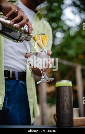 Der männliche Barkeeper schüttet Limonade in den Cocktail, während er draußen ist Stockfoto
