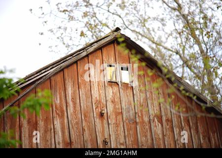 Pediment aus braunen Brettern in einem Landhaus. Kleine Fenster auf dem Dachboden. Stockfoto