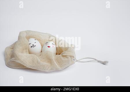 Wunderschön bemalte Ostereier liegen in einer umweltfreundlichen Netztasche mit Kordelzug auf einem weißen Tisch. Lustige Pik auf Eier gemalt. Speicherplatz kopieren. Frohe Feiertage Stockfoto
