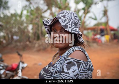 Porträt einer lächelnden, reifen Afrikanerin in traditioneller Kleidung und mit Hut Stockfoto