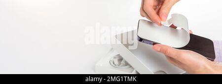 Ein neues Telefon auspacken. Entfernen Sie die weiße Schutzfolie vom neuen Telefon. Nahaufnahme der Hände einer Frau, die einen Schutzfilm von einem Telefon in einem entfernt hat Stockfoto