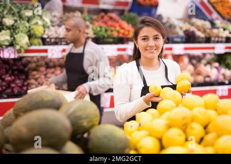 Lächelnde Supermarktarbeiter in der Obst- und Gemüseabteilung Stockfoto