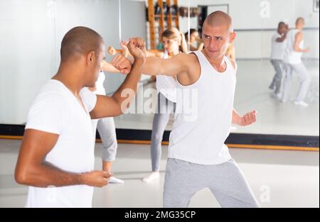 Männer üben grundlegende Bewegungen während des Selbstverteidigungskurses im Fitnessstudio Stockfoto