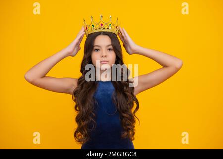 Teenager Prinzessin Kind feiert Erfolg Sieg und Sieg. Teen Mädchen in Königin Krone auf gelbem Hintergrund isoliert. Stockfoto