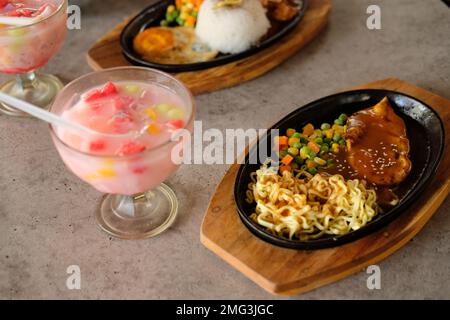 Nahaufnahme einer Schüssel Soba-Nudeln mit Rindersteak und Eisfrucht. Köstliche asiatische Küche mit Eisfrucht auf dem Tisch Stockfoto