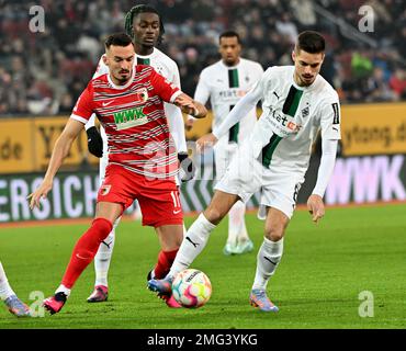 Augsburg, Deutschland. 25. Januar 2023. Fußball: Bundesliga, FC Augsburg - Bor. Mönchengladbach, Spieltag 17, WWK Arena. Augsburgs Mergim Berisha (l) und Julian Weigl (r) aus Mönchengladbach. Kredit: Peter Kneffel/dpa - WICHTIGER HINWEIS: Gemäß den Anforderungen der DFL Deutsche Fußball Liga und des DFB Deutscher Fußball-Bund ist es verboten, im Stadion aufgenommene Fotos und/oder das Spiel in Form von Sequenzbildern und/oder videoähnlichen Fotoserien zu verwenden oder verwenden zu lassen./dpa/Alamy Live News Stockfoto