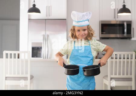 Lustige Kinderküche. Lustige kleine Köchin Koch trägt Uniform Kochmütze und Schürze gekochtes Essen in der Küche. Die Kinder bereiten Essen zu, backen Kekse Stockfoto