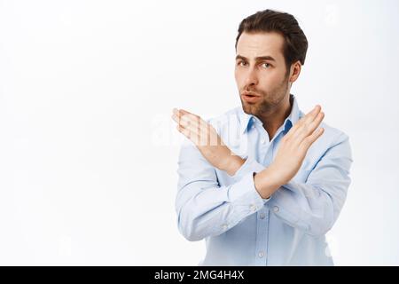 Bitte hör auf. Ein ernster Mann besteht darauf, dass du kündigst, ablehnst, etwas verbietet, Kreuzgesten machst, über weißem Hintergrund stehst Stockfoto