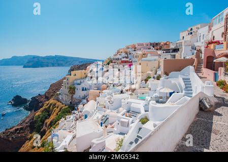 Santorin, Griechenland. Malerischer Blick auf die traditionellen kykladischen Häuser von Santorin in einer kleinen Straße mit Blumen im Vordergrund Stockfoto