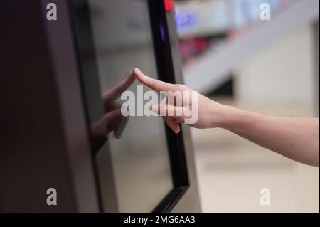 Gesichtslose Frau mit Touchscreen-Geldautomat. Stockfoto