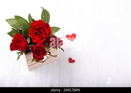 Strauß roter Rosen im Holzkasten auf weißem Hintergrund Stockfoto