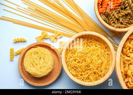 Schüsseln mit verschiedenen Arten roher Pasta auf hellem Hintergrund, Nahaufnahme Stockfoto