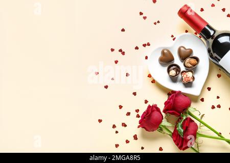 Flasche Wein, Schokoladenbonbons und Rosenblumen auf beigefarbenem Hintergrund. Valentinstag-Feier Stockfoto