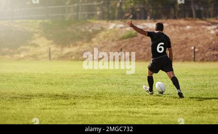 Rugby, Spieler und Kick einen Sportball auf einem Feld während des Trainings, Trainings oder Trainings im Freien. Sportler, Sportler und Mann während eines Spiels, bei dem ein Stockfoto