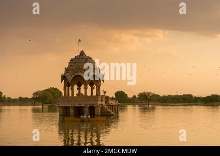 Chhatris und Schreine der hinduistischen Götter und Göttinnen am Gadisar-See, Jaisalmer, Rajasthan, Indien mit Reflexion über Wasser. Indoislamische Architektur. Stockfoto