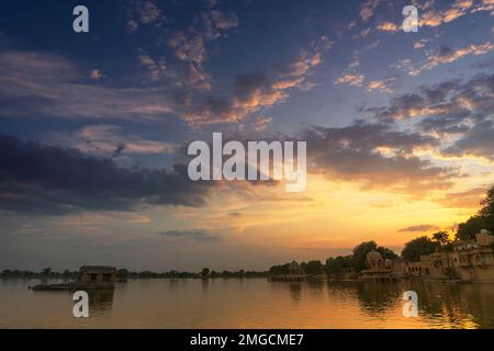 Schöner Sonnenuntergang am Gadisar Lake, Jaisalmer, Rajasthan, Indien. Untergehende Sonne und bunte Wolken am Himmel mit Blick auf den Gadisar See. Stockfoto