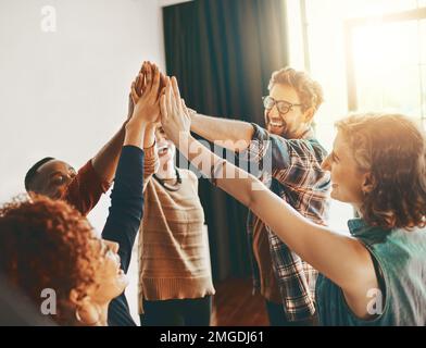 Wenn Sie kleine Unternehmen unterstützen, unterstützen Sie einen Traum. Kreative Mitarbeiter geben sich gegenseitig im Büro ein High-Five. Stockfoto