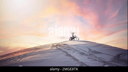 Wüste, Sonnenuntergang und Motorradfahrer für Sport, Fitness oder Training in der Natur. Extremsport, Dämmerung und männlicher Sportler auf einem Fahrrad für einen Stockfoto