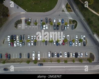 Belebter großer moderner Parkplatz mit symmetrischen Straßen Reihen von Parkbuchten viel Symmetrie und Farben aus der Vogelperspektive von der Drohne nach oben mit Blick nach unten. Stockfoto