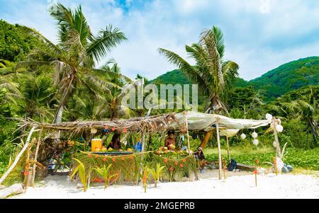 La Digue Seychellen 2018. März, Leute, die Kokosnussgetränke am Strand von Grand Anse verkaufen Stockfoto