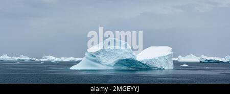 Eisberge, jeder ganz individuell, wie handgefertigte Eisskulpturen, schweben leise über das Meer der Antarktis. Stockfoto