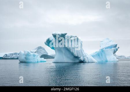 Eisberge, jeder ganz individuell, wie handgefertigte Eisskulpturen, schweben leise über das Meer der Antarktis. Stockfoto