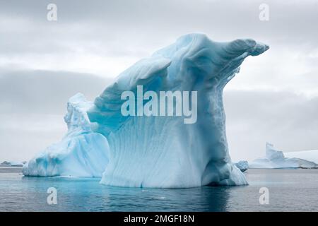 Eisberge, jeder ganz individuell, wie handgefertigte Eisskulpturen, schweben leise über das Meer der Antarktis. Stockfoto