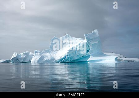 Eisberge, jeder ganz individuell, wie handgefertigte Eisskulpturen, schweben leise über das Meer der Antarktis. Stockfoto