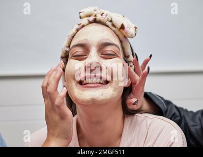 Gesichtspflege, Spa und Hautpflege durch eine Frau mit einer Gesichtsmaske zur Schönheitsbehandlung als Selbstpflege durch Kosmetikerin. Wellness, Peeling und Kosmetiksalon für ein glückliches Stockfoto