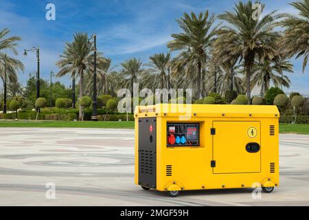 Big Yellow außerhalb des elektrischen Hilfstromaggregats Dieseleinheit für den Notfall auf einer leeren City Street mit Palmen extreme Nahaufnahme auf einem weißen Stockfoto