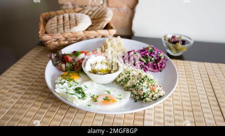 Israelische Kombi-Platte mit Eiern, Tabbouleh, Rotkohlsalat und Pita-Brot. Stockfoto