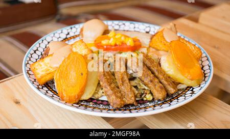 Afrikanische Kombi-Platte mit Reis, gebratenem Käse, gegrilltem Gemüse, Erdnusssoße und anderen traditionellen Produkten. Stockfoto