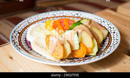 Afrikanische Kombi-Platte mit Reis, gebratenem Käse, gegrilltem Gemüse, Erdnusssoße und anderen traditionellen Produkten. Stockfoto