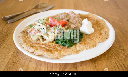 Goraasa-Brötchen mit Gemüse. Goraasa ist ein sudanesischer Pfannkuchen oder Fladenbrot, der flauschig, vielseitig, weich und dünn ist. Stockfoto